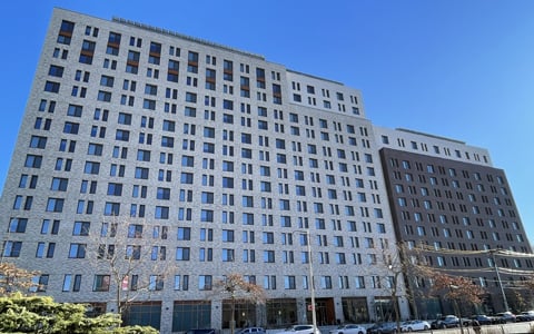 Large building with multiple windows surrounded by blue skies.
