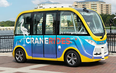 A blue and yellow autonomous vehicle with the words Crane Rides on the side