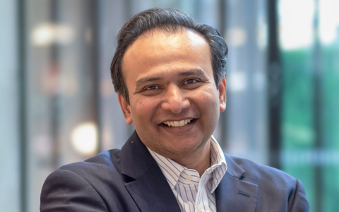 Amir Rizavi smiling in a blue suit. 