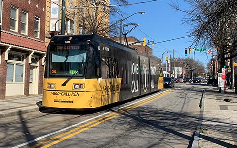 A modern streetcar runs through a street in Atlanta lined with historic buildings