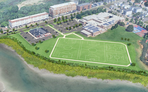 Aerial view of a green sports complex featuring multiple soccer fields with marked goals. Surrounding the fields is a pathway. 