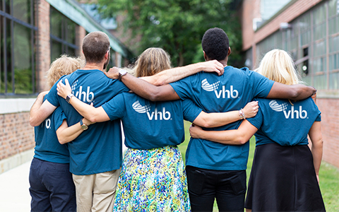 Five VHB employees standing side by side wearing blue VHB t-shirts