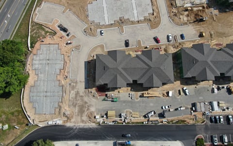 Construction progress shows two completed apartment buildings, parking lot, and the future location of two more buildings.