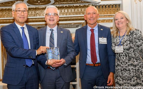 Four individuals smiling at the camera holding an award.