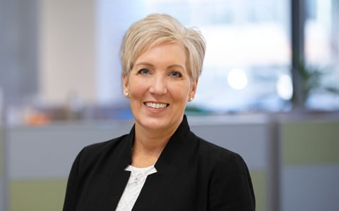 Woman with short, blonde hair with a black suit and white top.