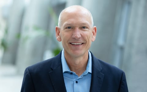 Bill Ashworth smiling in a navy blazer and checkered shirt.