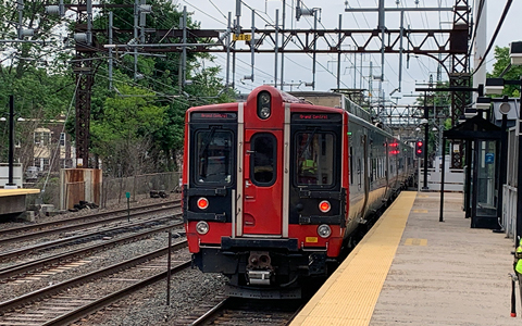 Red train on railroad tracks at a train station platform.