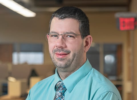 Dan Parent smiling in a blue shirt and tie.