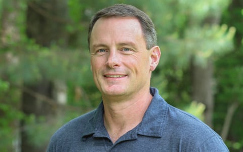 Doug DeBerry smiling at the camera in a blue polo shirt.