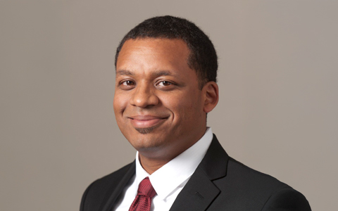 Fyiad Constantine smiles at the camera wearing a suit and tie.