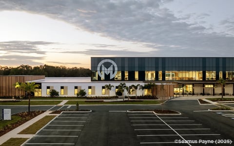 A healthcare building with an M on its exterior facade at sunset.