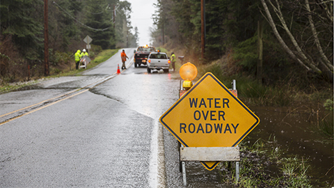 Emergency workers placing warning signs on flooded road