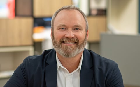 J.D. Hines smiling in a navy blazer with a white button down.