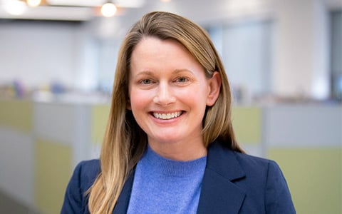 Woman with a blue sweater standing in an office.