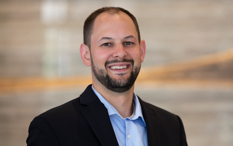 Josh Bendyk with a beard in a blue shirt and black suit.