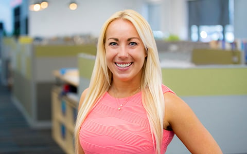 Kathleen wears a pink blouse in an office setting