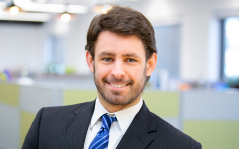 Ken Donald in a blue striped tie standing in an office.