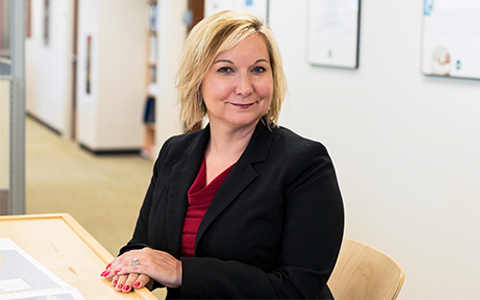 Professional Headshot of Kirsten Tynch Sitting at Table in Black Blazer