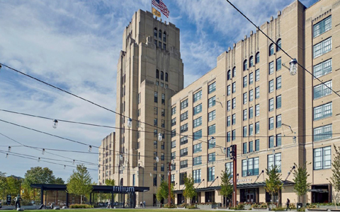 An industrial city building with two flags flying.