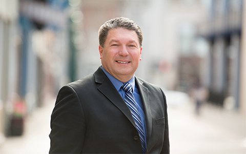 Larry Spraker in a dark blazer and blue shirt.