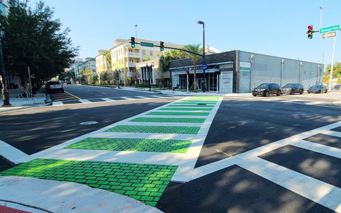 A bright green bicycle and pedestrian path on a city street.