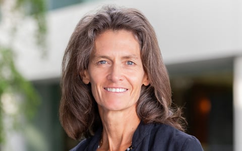 Megan Raymond in an office setting wearing a navy-blue top. 