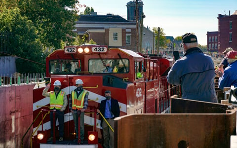 VHB and VTrans crew ride train through Middlebury, VT with excited town members watching following successful construction. 