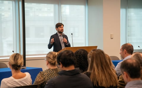 Ryan Prime speaking at an event in front of crowd. 