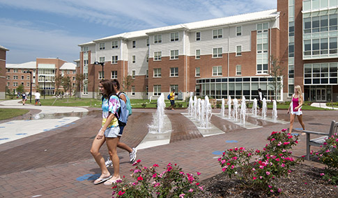 Students pass a water feature as they walk through Old Dominion University’s campus on a sunny day 