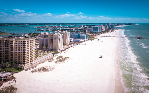 A strip of white sandy Clearwater beach with buildings at the ocean’s edge