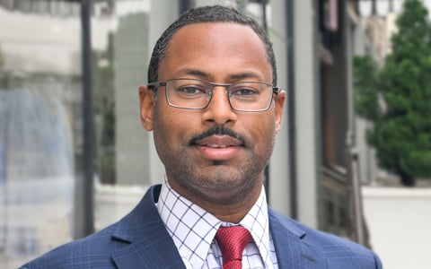 Ravi Amin in a blazer and glasses.