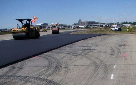 Construction progress at Runway 16-34 shows new pavement, with a view of Rhode Island T.F. Green Airport in the distance.