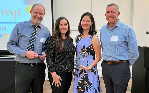 Two women and two men standing together with two awards.