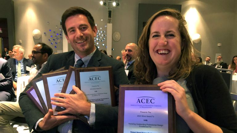 Two employees at an event dinner holding engineering awards