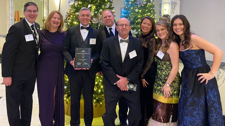Group of VHB staff with award in front of Christmas tree at the 2025 ACEC/MW Engineering Excellence Awards Gala on December 16