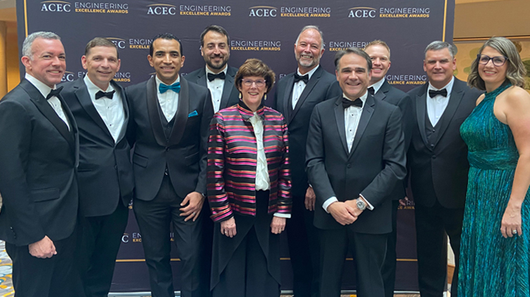 A group of VHBers stand together at the awards ceremony smiling at the camera. 
