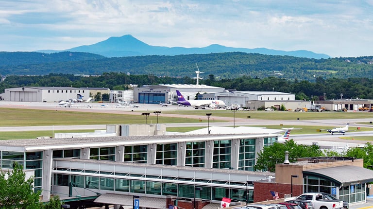 Airport buildings and runways with mountains in the background.