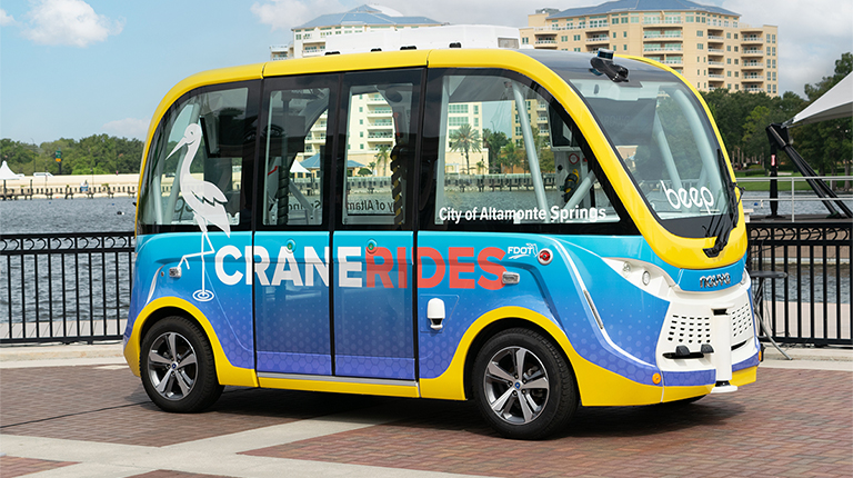 A blue and yellow autonomous vehicle with the words Crane Rides on the side