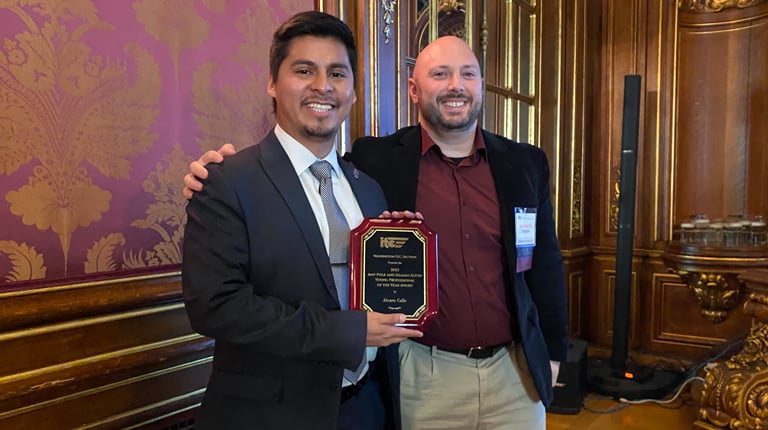 Alvaro Calle smiles at the camera holding his award plaque.