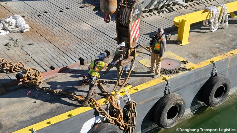 Three men in protective gear overseeing the recovery of a lost anchor out of the channel.