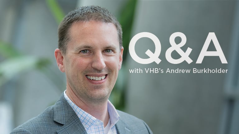 Andrew Burkholder smiling in a gray blazer and checked collared shirt.