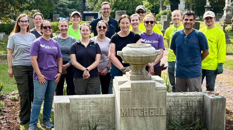 A group of VHB employees stand around a cemetery headstone.