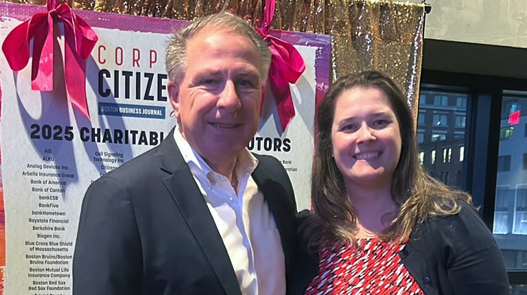 Two individuals at a corporate event smiling and holding a Corporate Citizenship Award.