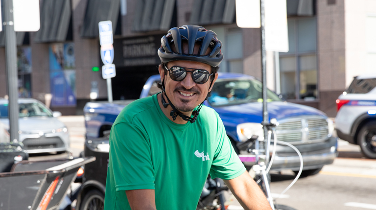 Jaime Igua wears a green VHB shirt and bike helmet.