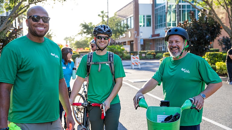 Three VHB team members in green shirts standing by bicycles