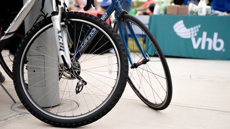 Two bicycles parked near a VHB display at an outdoor event.