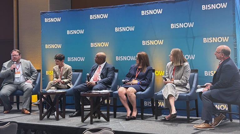 A panel of six individuals seated on a stage with a "Bisnow" backdrop.