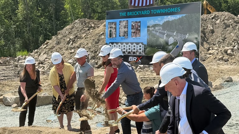 Governor Ayotte in a red dress, leading a group in a groundbreaking ceremony.
