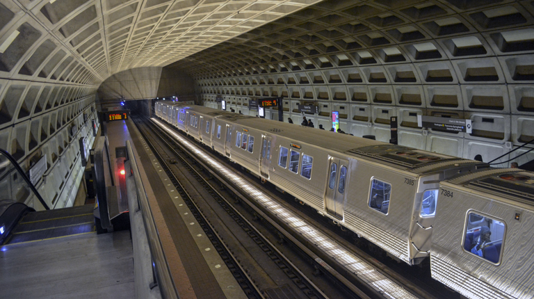 The existing Metrorail station train platform with a train stopped for riders.