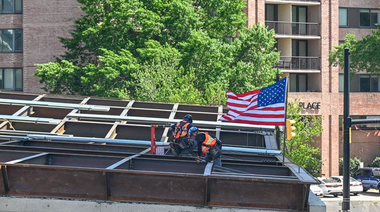 Construction workers place the signed beam in place at the CCEE.